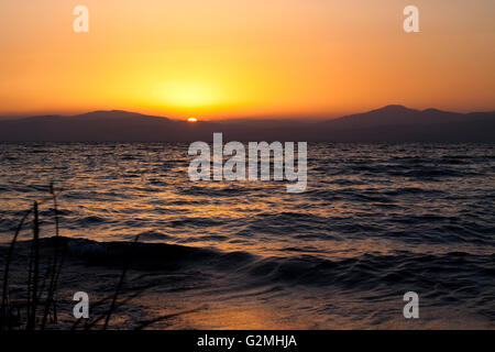 Susnet sopra la montagna e il sole che riflette in mare Foto Stock