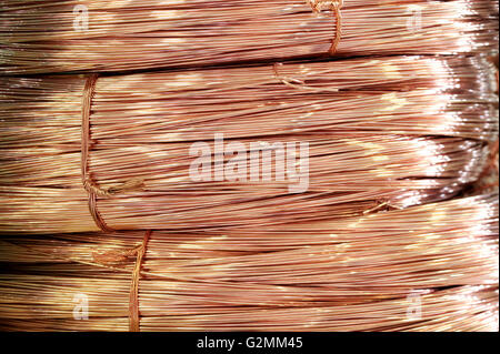 Close up sulle bobine di lucido di filo di rame memorizzate come materia prima di alimentazione in metallo per uso nella produzione industriale o cablaggi elettrici Foto Stock