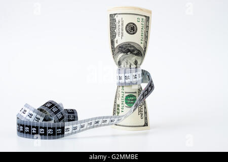 Un mazzetto di fatture del dollaro tightend mediante un nastro di misurazione su sfondo bianco Foto Stock