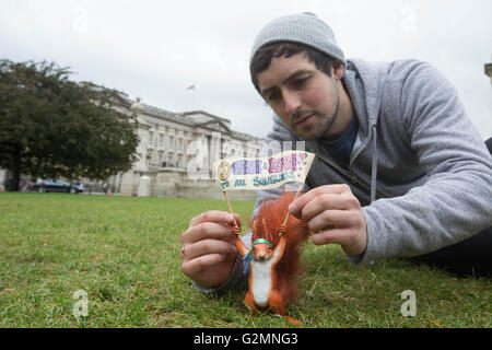 Solo uso editoriale l'artista di strada Marcus Crocker regola una scultura in miniatura di Beatrix Potter carattere Nutkin scoiattolo al di fuori del Buckingham Palace di Londra, che è stato aggiornato per il XXI secolo nella celebrazione del centocinquantesimo anniversario dell'autore della nascita. Foto Stock