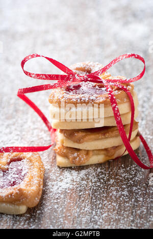 Un mucchio di cuore i cookie su una tavola in legno rustico. È possibile utilizzarlo per un biglietto di auguri o ricetta. Foto Stock