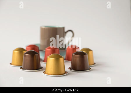 Varietà di cialde di caffè con fuori fuoco tazzina contro uno sfondo bianco Foto Stock
