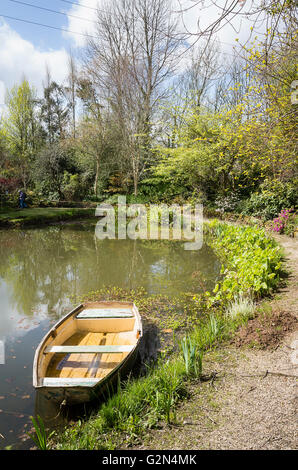 Ampio giardino sul lago con il vecchio legno barca a remi in un giardino privato in Cornovaglia Foto Stock