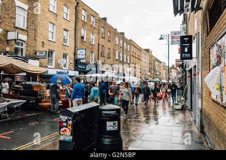 Londra, UK, 23 agosto 2015: Persone a Brick Lane le bancarelle del mercato di una giornata piovosa. Quasi tutto può essere trovato su Brick Lane. Foto Stock