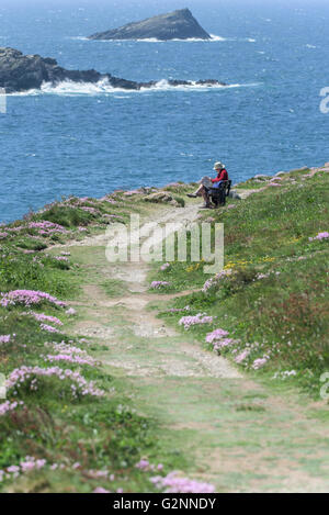 Tempo soleggiato come walkers prendere un periodo di riposo su una panchina accanto a un sentiero usurati su East Pentire in operazioni automatiche di fine campo, Newquay Cornwall. Foto Stock