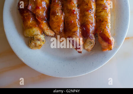 Pancetta avvolto i filetti di pollo in smalto miele disposti sulla piastra Foto Stock