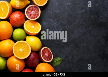 Fresche e mature agrumi. I Limoni e limette e le arance in pietra scura sullo sfondo. Vista da sopra con lo spazio di copia Foto Stock