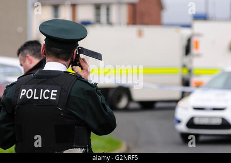 Un PSNI funzionario di polizia effettua una chiamata telefonica durante una bomba spaventare avviso di protezione nel Rathcoole, IRLANDA DEL NORD, Regno Unito 26/02/2012 Foto Stock