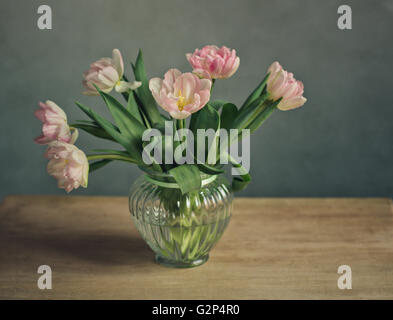 Bouquet di belle color pastello rosa tulipani in vasi di vetro decorativo e il cestello di metallo Foto Stock