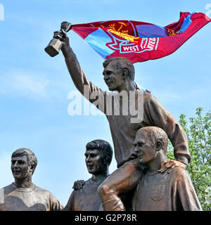 Parte della Coppa del mondo di football giocatori scultura statua con Bobby Moore con World Cup Trofeo e tifosi West Ham banner fisso alla tazza in Upton Park Foto Stock
