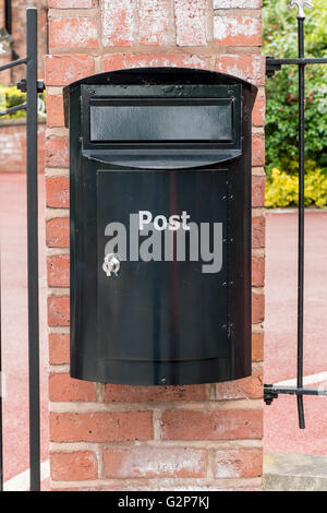 Nero casella di posta su un muro di mattoni Foto Stock