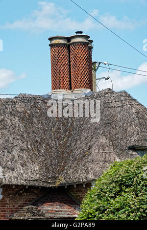 Curioso piccolo cottage con il tetto di paglia con interessanti camini Foto Stock