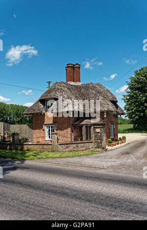 Curioso piccolo cottage con il tetto di paglia con interessanti camini Foto Stock