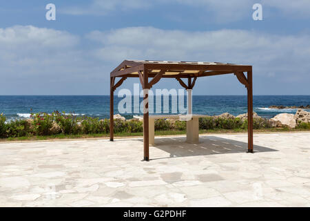 Piccolo padiglione in legno con tavolo sulla rocciosa spiaggia del mare Foto Stock