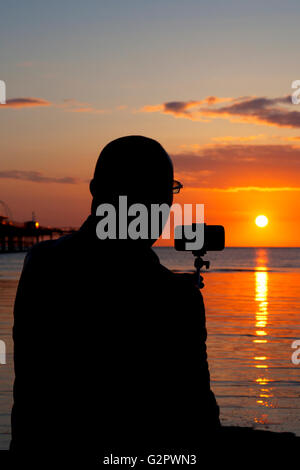 Southport, Merseyside, Regno Unito. 02Giugno, 2016. Un uomo prende le immagini del sole al largo della costa di Southport nel Merseyside. Utilizzando il suo telefono il lasso di tempo funzione che è stata in grado di catturare il tramonto perfetto. Credito: Cernan Elias/Alamy Live News Foto Stock