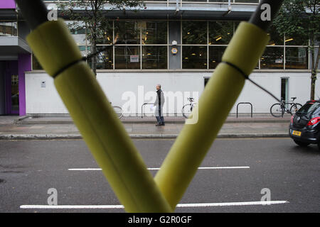 L'uomo cammina oltre la London Metropolitan University di Holloway, a nord di Londra, visto attraverso un ponteggio poli Foto Stock