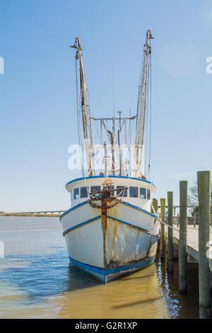 Shrimping vecchia barca accanto ad un molo con vista oceano in background Foto Stock