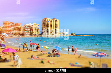 TORREVIEJA, Spagna - 13 settembre 2014: Sunny mediterranean beach, turisti rilassarvi sulla sabbia calda sulle sedie a sdraio sotto gli ombrelloni Foto Stock