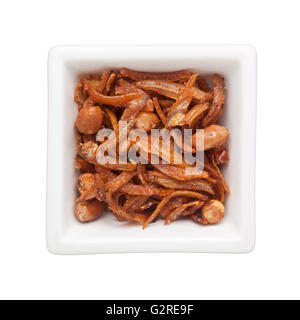 Alici fritte e arachidi in un recipiente quadrato isolato su sfondo bianco Foto Stock