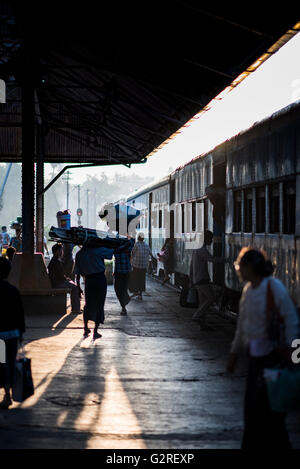 Silhouette di persone con bagagli in attesa per la partenza del treno a Yangon Stazione Ferroviaria Centrale, Myanmar. Foto Stock