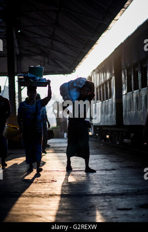 Silhouette di persone con bagagli in attesa per la partenza del treno a Yangon Stazione Ferroviaria Centrale, Myanmar. Foto Stock