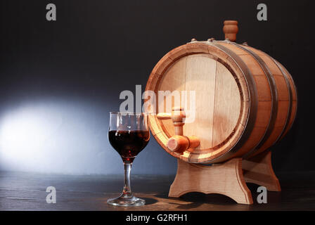 Bella botte di rovere vicino wineglass con vino rosso su sfondo scuro Foto Stock