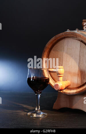 Bella botte di rovere vicino wineglass con vino rosso su sfondo scuro Foto Stock