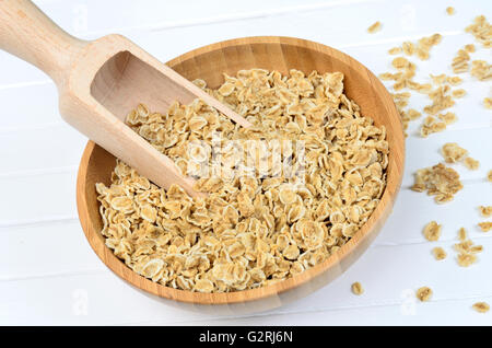 Ciotola di bambù con avena e scoop su bianco tavolo in legno Foto Stock