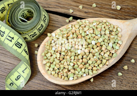 Il verde del grano saraceno in un cucchiaio di legno e centimetro su tavola Foto Stock