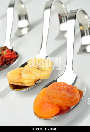 Frutta secca in un cucchiaio sul tavolo di legno Foto Stock