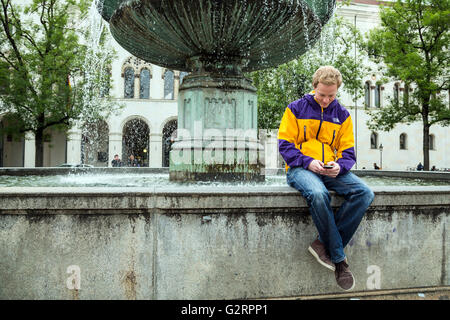 Muenchen, Germania, studente seduto da fontana sulla Geschwister-Scholl-Platz Foto Stock