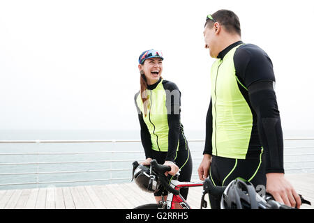 Felice coppia giovane con le bici a parlare e ridere sul molo Foto Stock