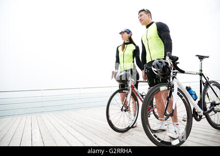 Bella coppia Giovane con le biciclette in piedi sul molo e tenendo le mani Foto Stock