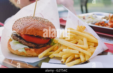 Fresh burger closeup su legno tavolo rustico con patate fritte e trucioli Foto Stock