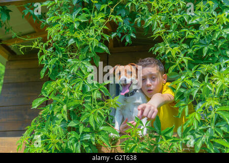 Ragazzo sorridente con il cane su treehouse. L'estate! Foto Stock