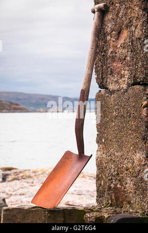 Un ritratto di formato di immagine una vanga appoggiato contro una parete con il Loch Torridon in background. Foto Stock