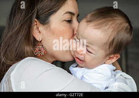 Giovane madre cercando di comfort e calma la sua baby boy. Foto Stock