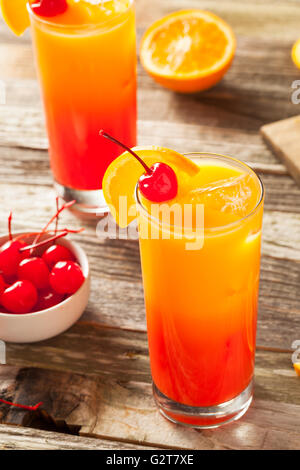 Succosa di colore arancione e rosso Tequila Sunrise con una ciliegia Foto Stock