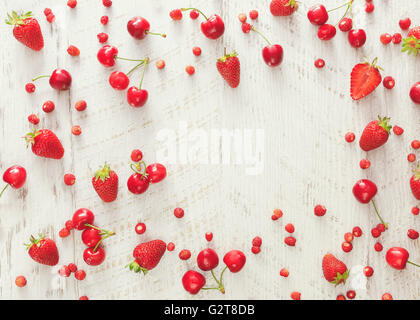 Frutti di bosco. Organici freschi frutti di bosco sparsi sul tavolo rustico con spazio per il testo nel mezzo. Vista aerea, spazio vuoto Foto Stock