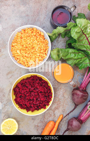 Carota succo di barbabietola e di insalata. Freschi barbabietole e carote, insalata e bicchieri di succo, vista dall'alto Foto Stock