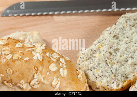 Appena affettato seminate integrali panini posa su una breadboard di legno con un coltello Foto Stock