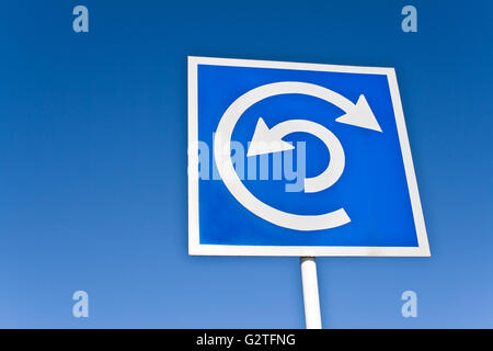 Rotatoria indicazione oltre il cielo blu Foto Stock