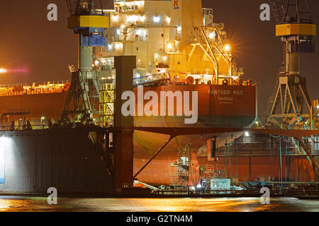 Nave da carico nel bacino galleggiante di Blohm e Voss, dal porto di Amburgo di notte, Amburgo, Germania Foto Stock