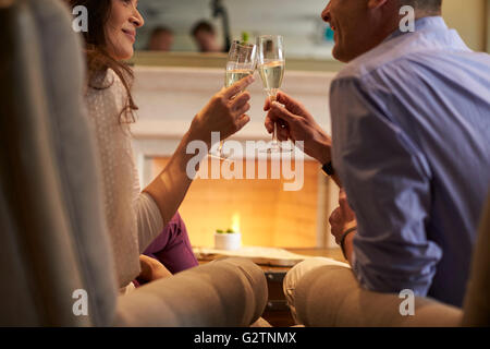 Coppia seduta dal fuoco facendo Toast con Champagne Foto Stock