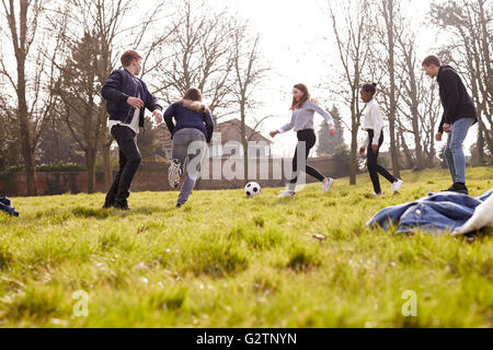 Un gruppo di ragazzi che giocano a calcio nel parco insieme Foto Stock