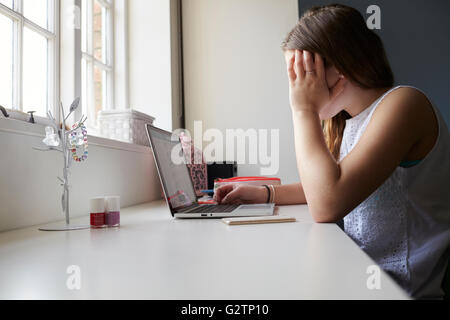 Adolescente infelice vittima di bullismo online in camera da letto Foto Stock