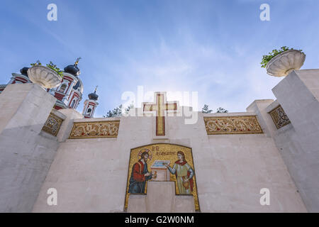 Grande Croce e acqua in primavera in ortodossi monastero Curchi in Moldavia con alberi verdi e blu cielo Foto Stock