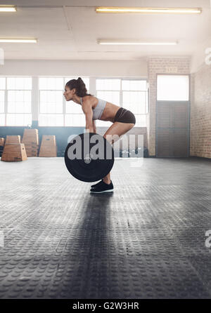 Vista laterale della donna fitness ginnastica con pesi pesanti in palestra. Donna muscolare praticare il sollevamento pesi al club della salute. Foto Stock