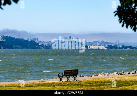 Una panchina nel parco con una vista mozzafiato dello skyline di San Francisco da Emeryville California's Powell Street. Foto Stock