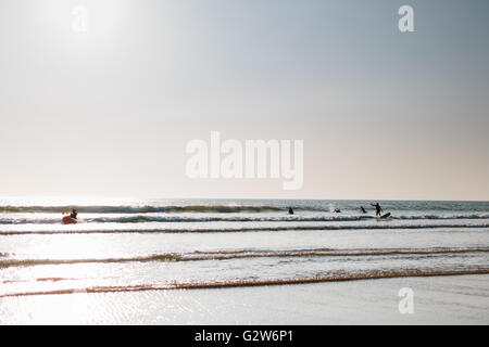 Surfisti cavalcare le onde piccole a Woolacombe Beach, Devon in una giornata di sole. Foto Stock